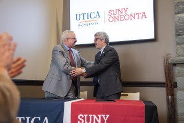 Utica University and SUNY Oneonta Presidents shake hands at the signing of an Articulation Agreement between the two schools on January 24, 2024.