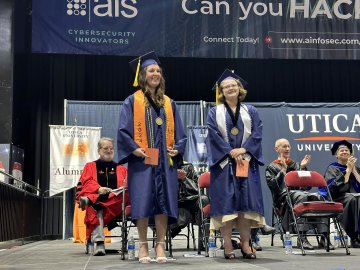 2024 Valedictorian Shayla Pominville and Salutatorian Sara Rachon stand on stage together at the 2024 Undergraduate Commencement ceremony.