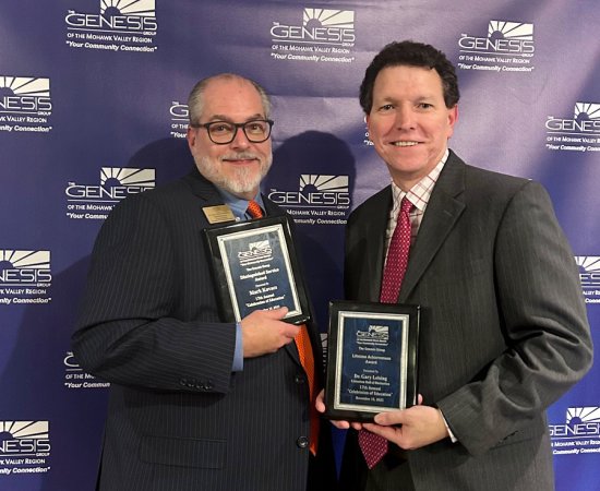 Mark Kovacs and Gary Leising hold up plaques at the Genesis Group's Celebration of Education event in November 2023.