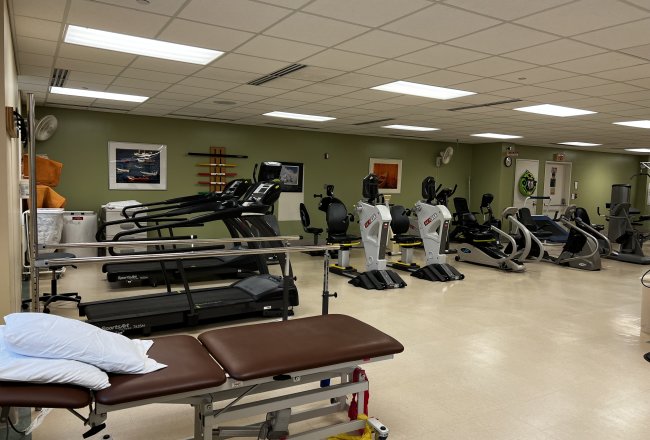 A room filled with gym equipment such as treadmills and stair machines used for orthapedic rehabilitation.