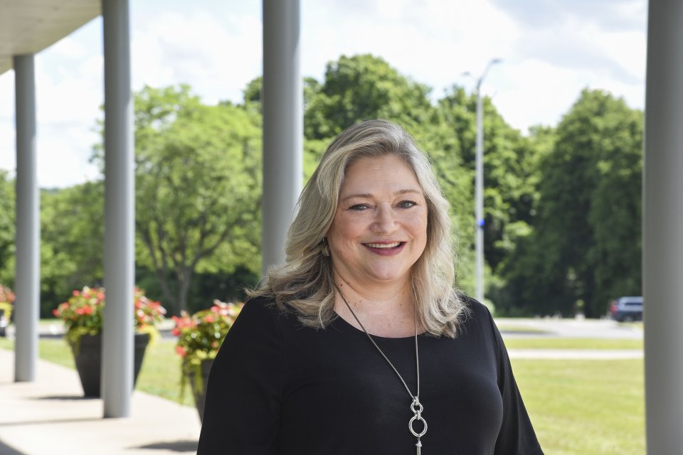 Leslie Corbo stands outside on campus, smiling.