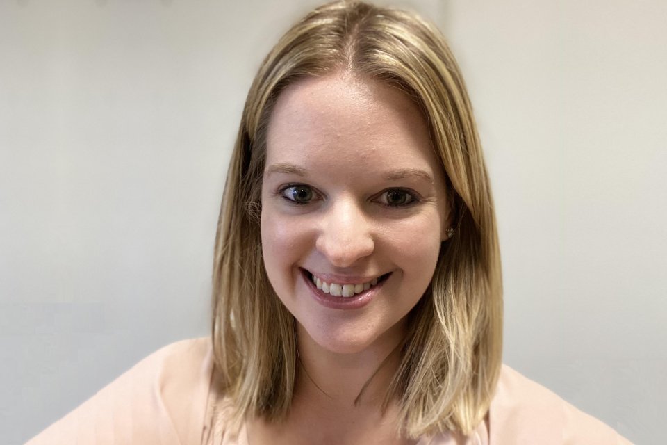 Sara Robinson, a young woman with shoulder-length blond hair, smiles at the camera in front of a beige wall.