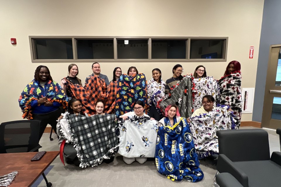 Members of the Title IX Team, Students, Faculty, and Staff show off Tie Blankets made to benefit domestic violence victims.