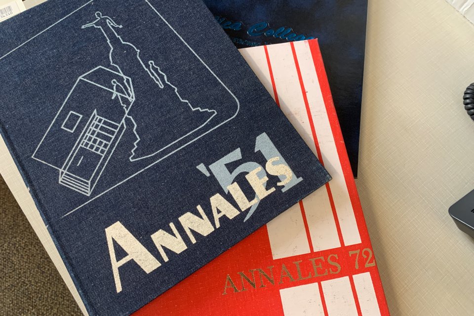 Copies of the Utica College 1951, 1972 and 1993 yearbooks stacked atop each other on a desk.